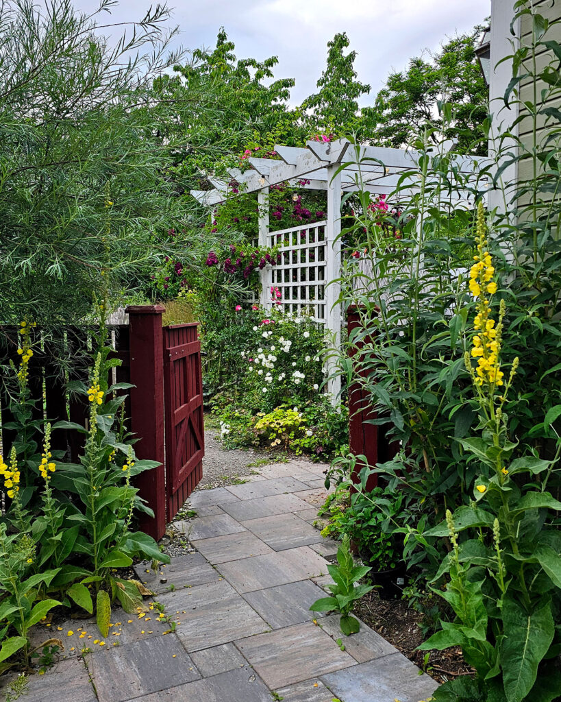 Trädgården på Villa Kämparo med gång mot köksträdgården och uteplats